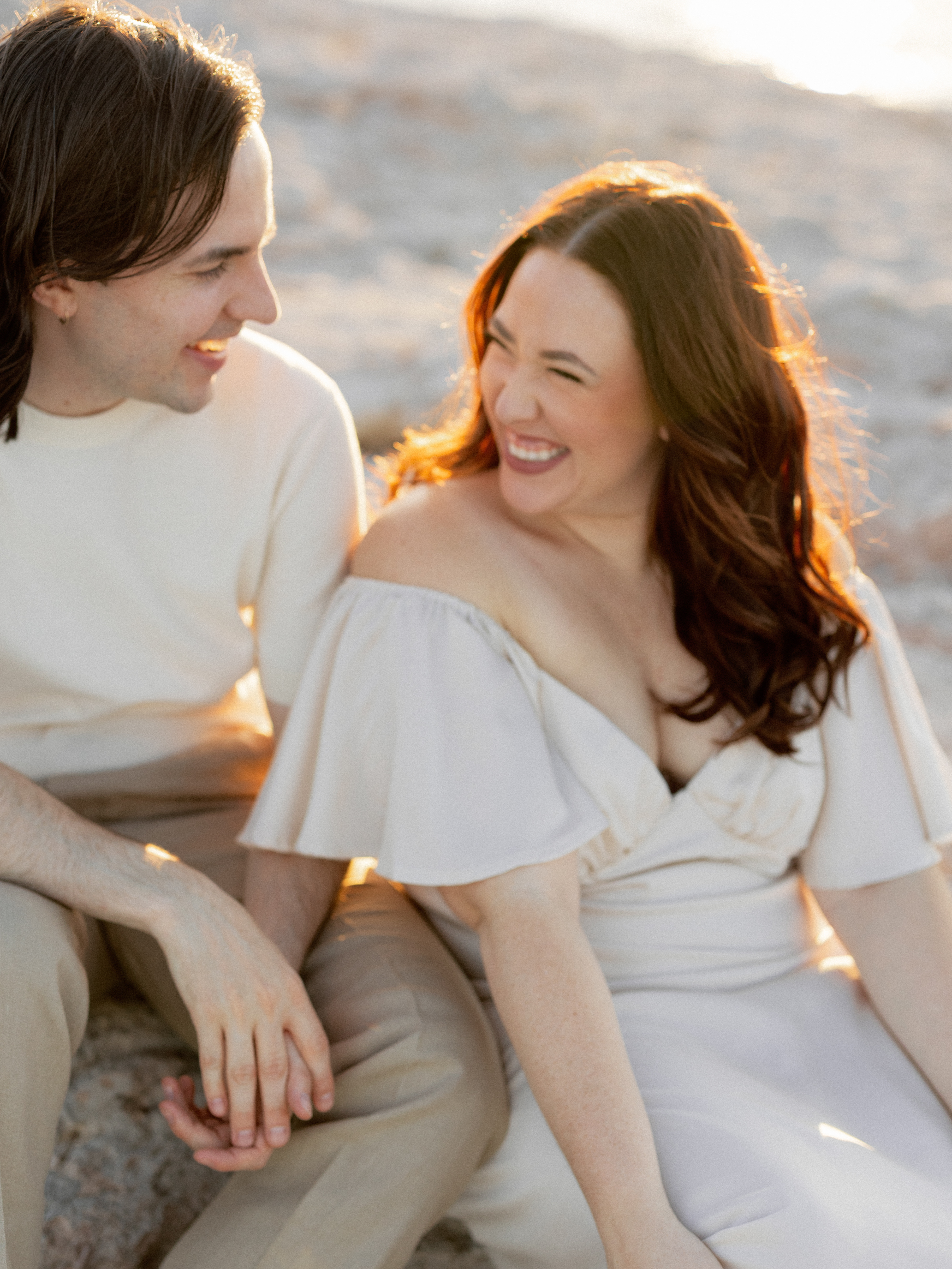 Amanda and Charlie sitting on the sand by a lake
