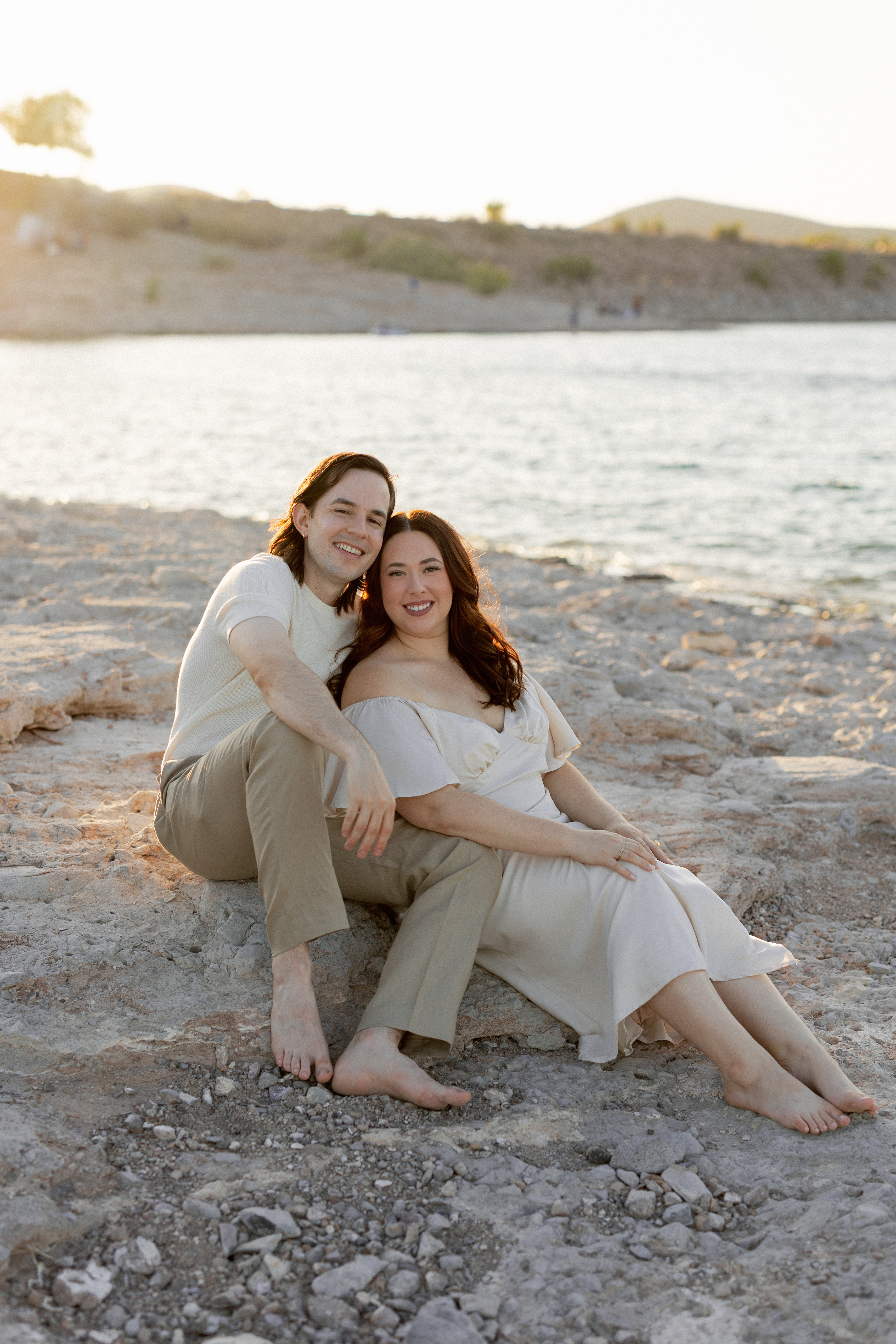 Amanda and Charlie sitting on the sand by a lake