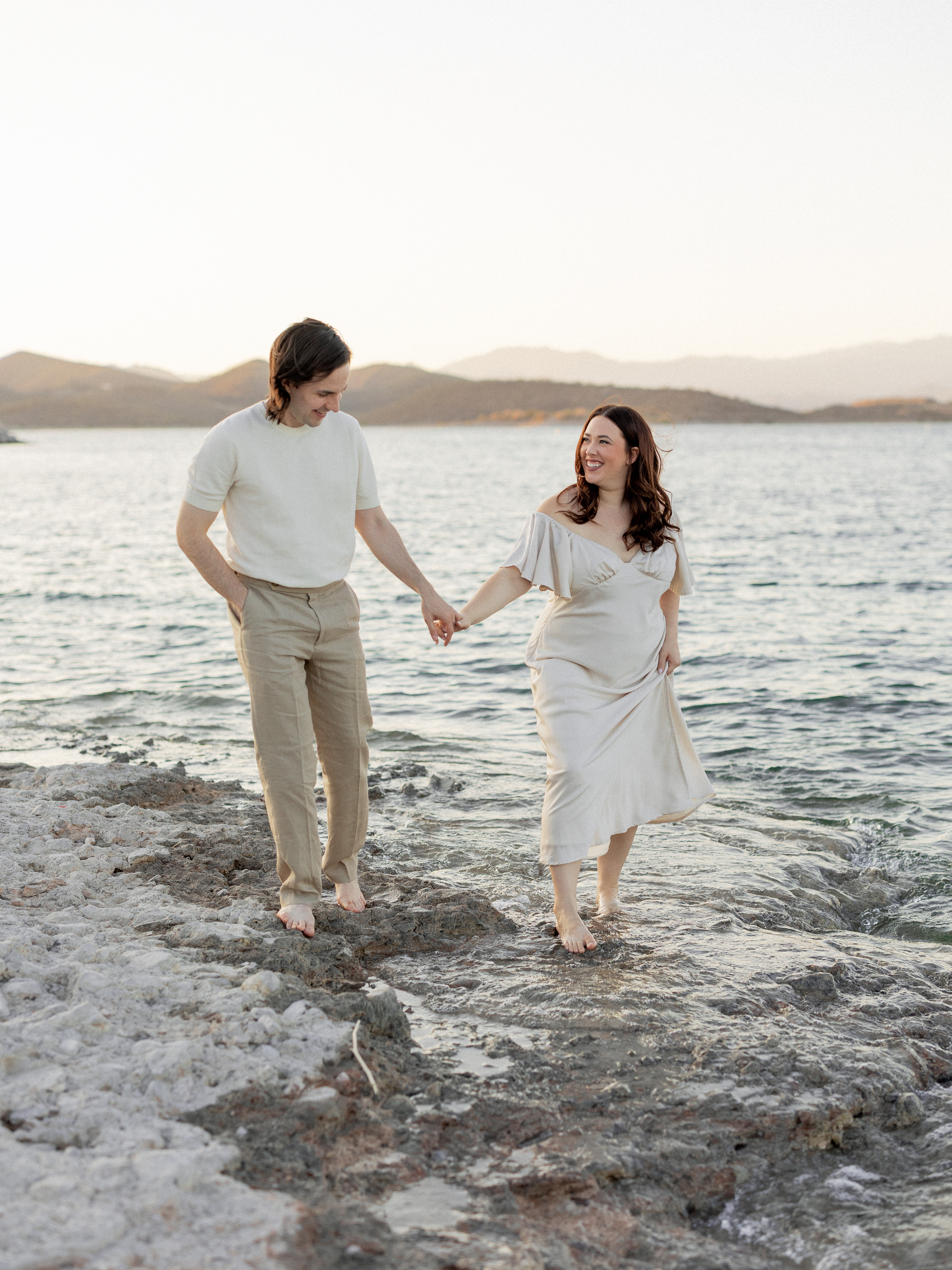 Amanda and Charlie walking on the sand by a lake